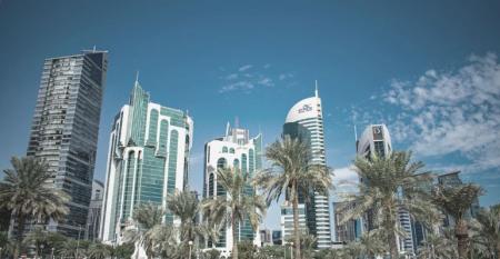 Doha Qatar city skyscrapers with palm trees and blue sky